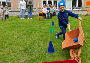 Dziecko przewozi slalomem w taczce żółwia.
