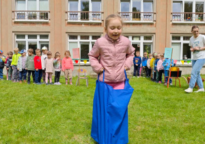 Dziecko pokonuje tor przeszkód, skacząc w worku.