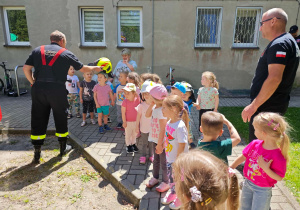 Dzieci przymierzają hełm strażacki.