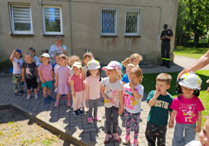Dzieci przymierzają hełm strażacki.