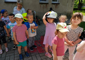 Dzieci przymierzają hełm strażacki.