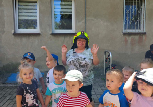 Dzieci i pani Jadzia przymierzają hełm strażacki.