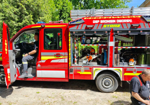 Dzieci słuchają syreny alarmowej wozu strażackiego.