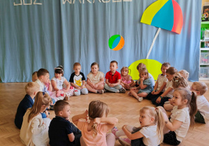 Dzieci siedzą w kole w oczekiwaniu na zabawę "Kąpiel w basenie".