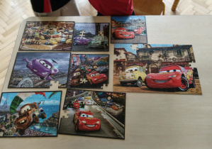 Na stoliku ułożone jest 8 puzzlowych obrazków.