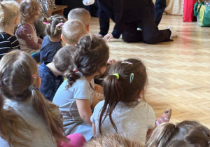 Dzieci biorą udział w spotkaniu z pluszowym kotem.